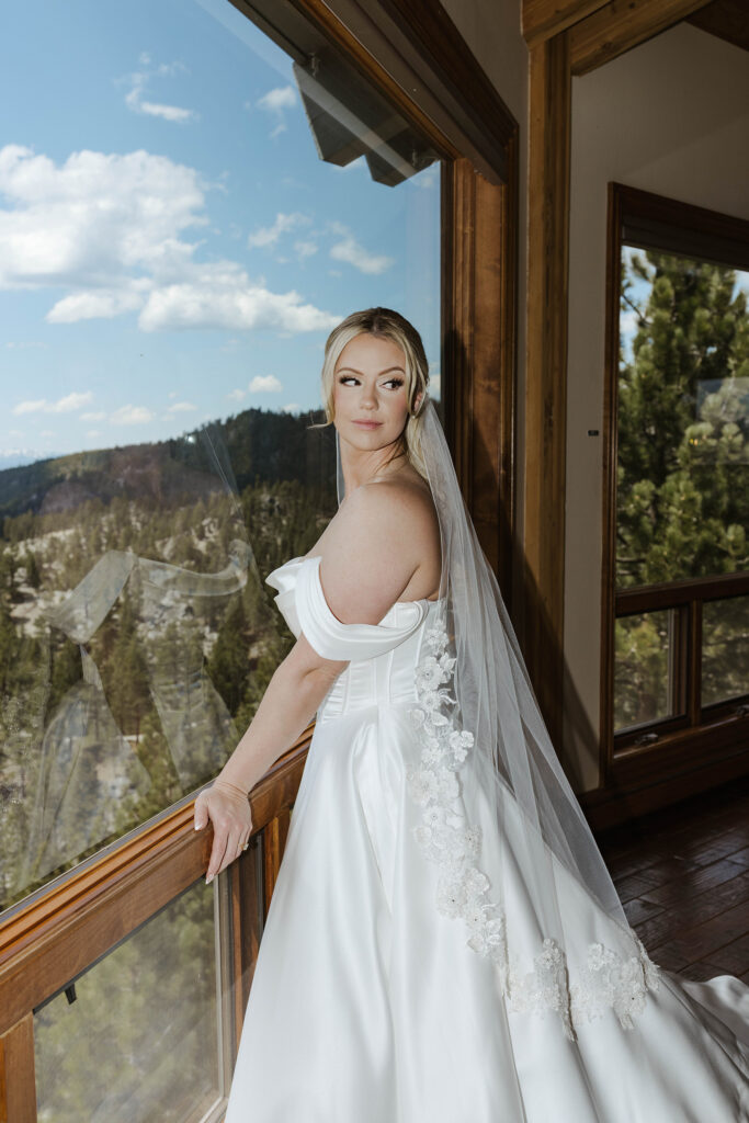bride leaning on the window looking over her shoulder wearing a white wedding dress at tahoe blue estate