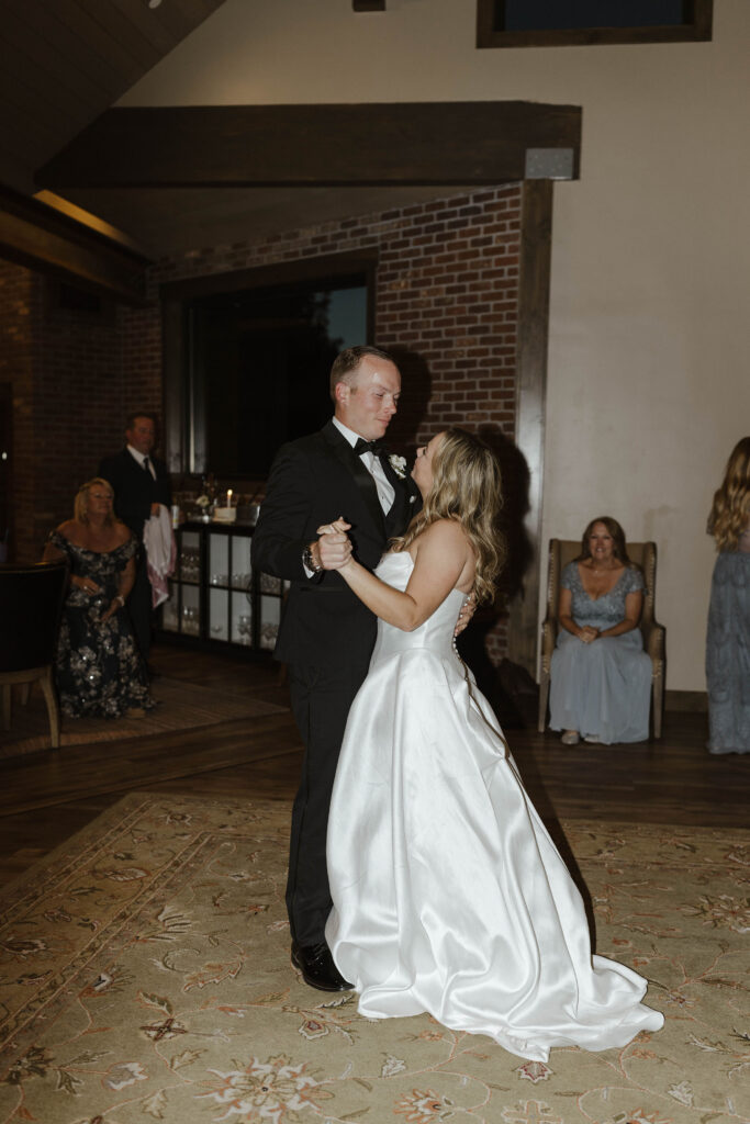newlyweds share a first dance in the living room with loved ones watching