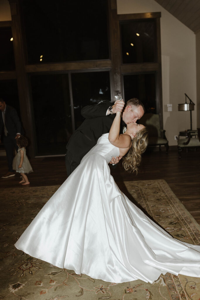 newlyweds do the dip kiss pose after sharing a first dance 
