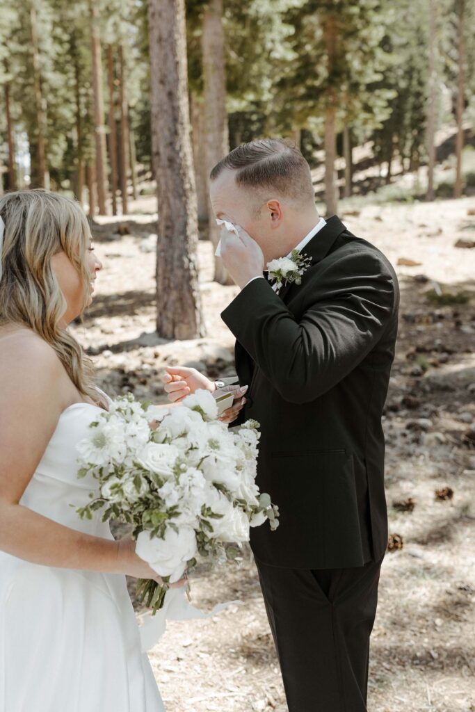 groom wiping his tears during a first look with his bride in donner lake 