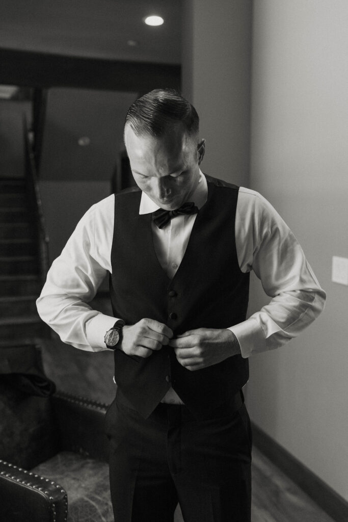 Groom buttoning his suit coat
