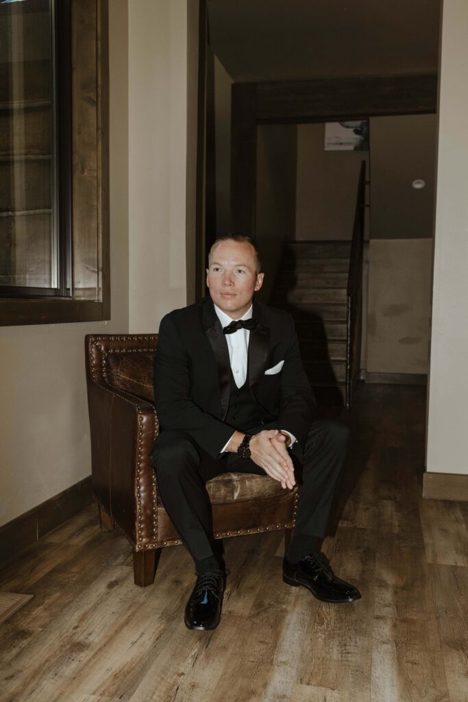 groom sitting on a chair looking off in the distance 