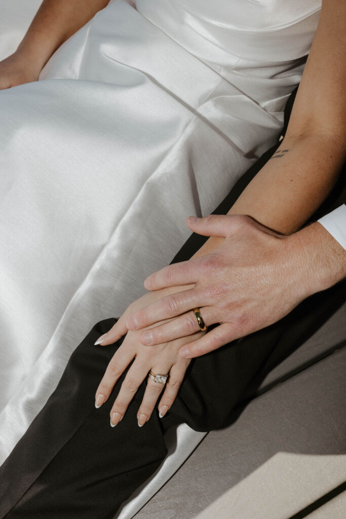 groom putting his hand on the brides hand showing wedding rings 