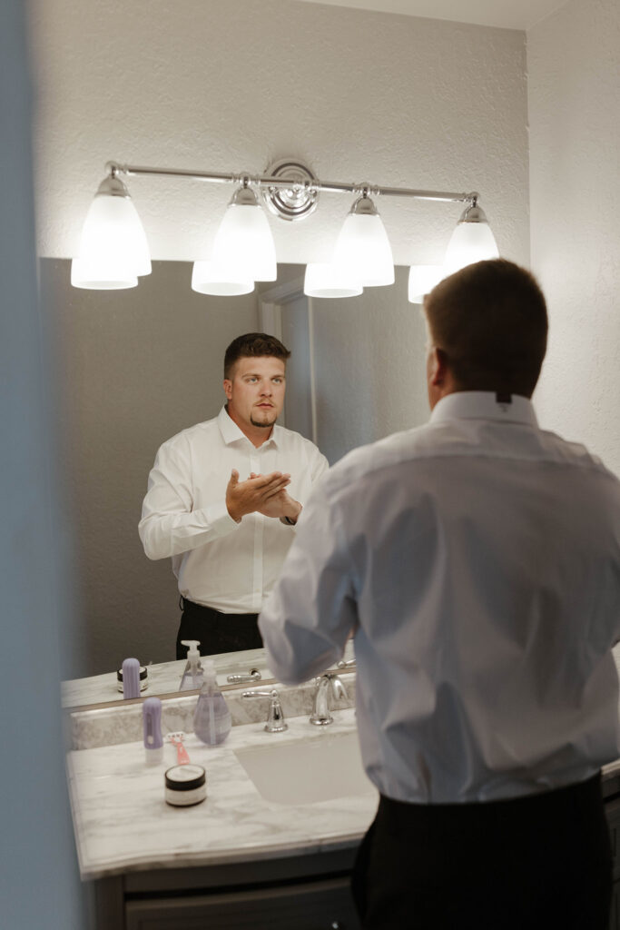 Groom looking in mirror while getting ready for elopement at Emerald Bay