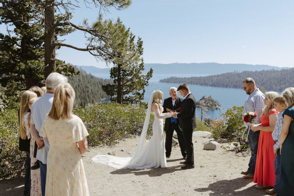 Elopement couple holding hands during ceremony at Emerald Bay with Lake Tahoe in background