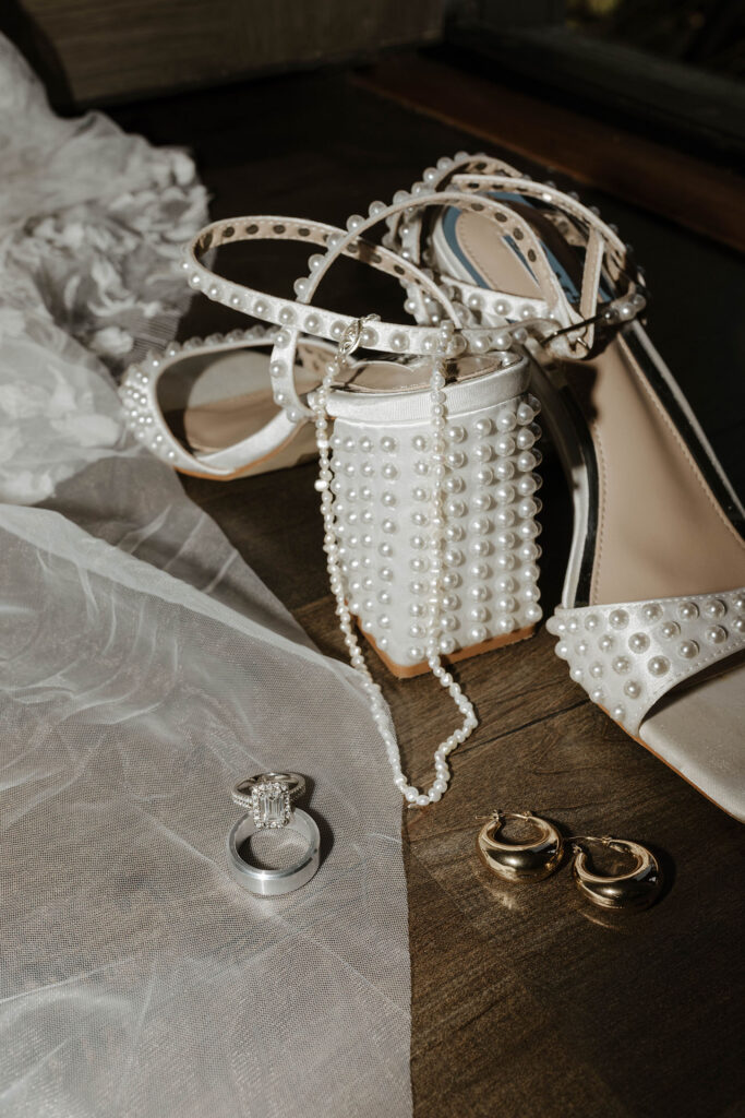 Bride's wedding shoes with pearl decorations next to veil and wedding jewelry at Emerald bay