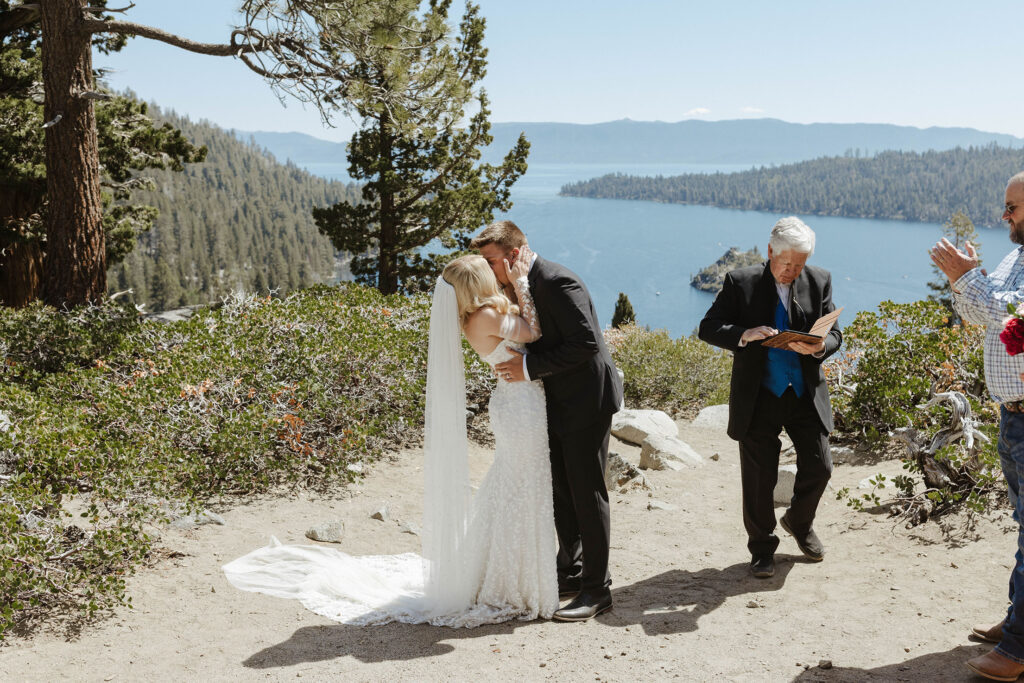 Elopement couple holding each other and kissing after ceremony at Emerald Bay with Lake Tahoe in background