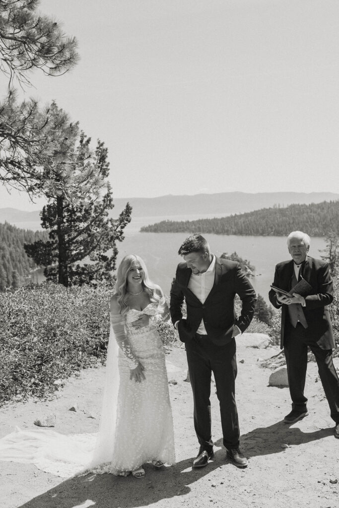 Elopement couple standing together while bride smiles after ceremony at Emerald Bay with officiant and Lake Tahoe in background