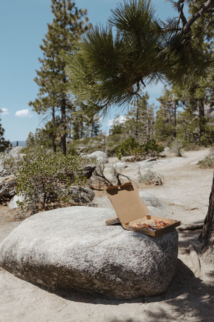 Pizza in a pizza box sitting on large rock at Emerald Bay