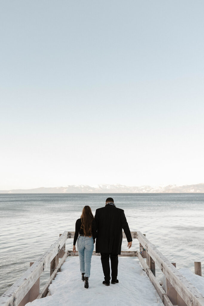 man and woman walking on a dock in the snow at valhalla lake tahoe