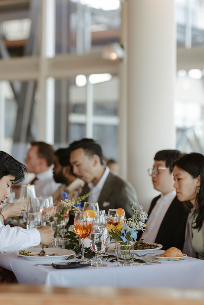 Wedding guests eating during reception at Palisades Tahoe with colorful flowers on table