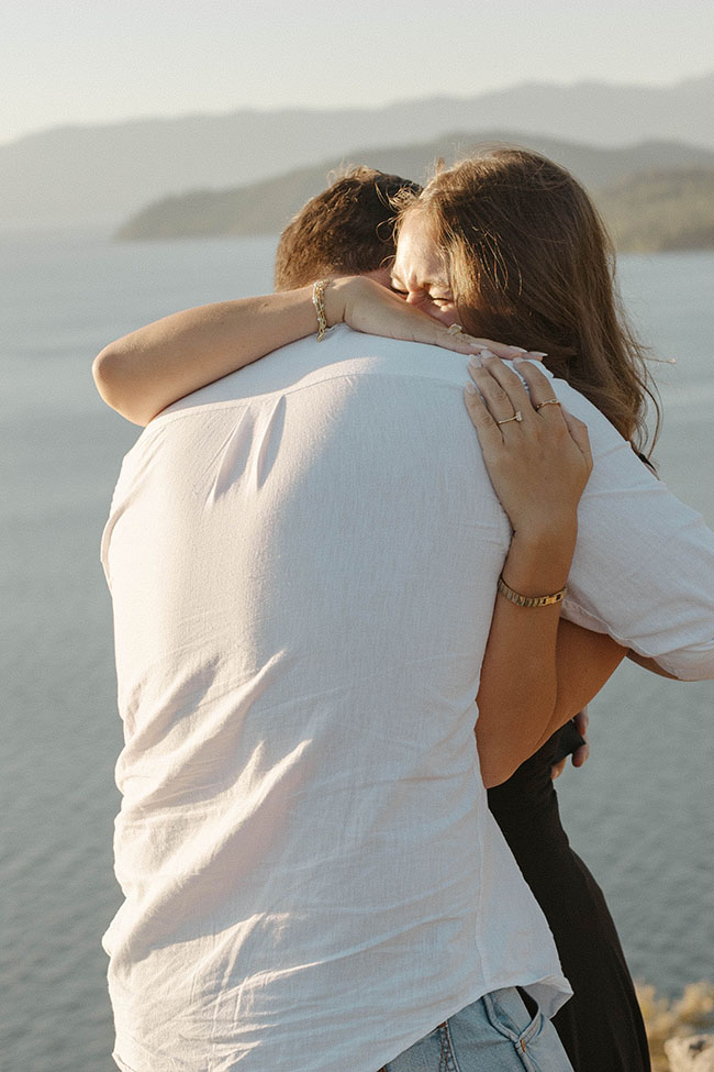 Couple hugging while woman is emotional after proposal at Eagle Rock with Lake Tahoe in background