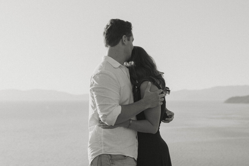 Couple hugging and holding each other while man kisses fiancé's head at Eagle Rock in Lake Tahoe