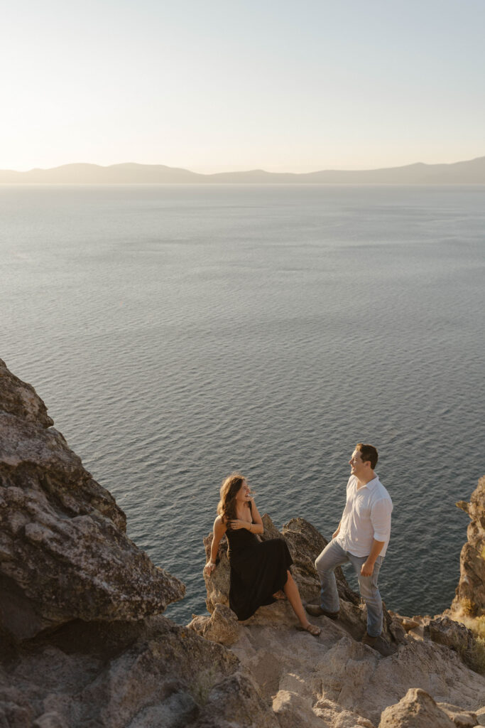 Engagement couple leaning on rocks and laughing together at Eagle Rock with Lake Tahoe in background