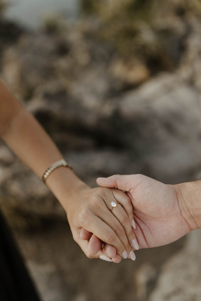 Close up of couple holding hands with engagement ring on woman's hand at Eagle Rock in Lake Tahoe
