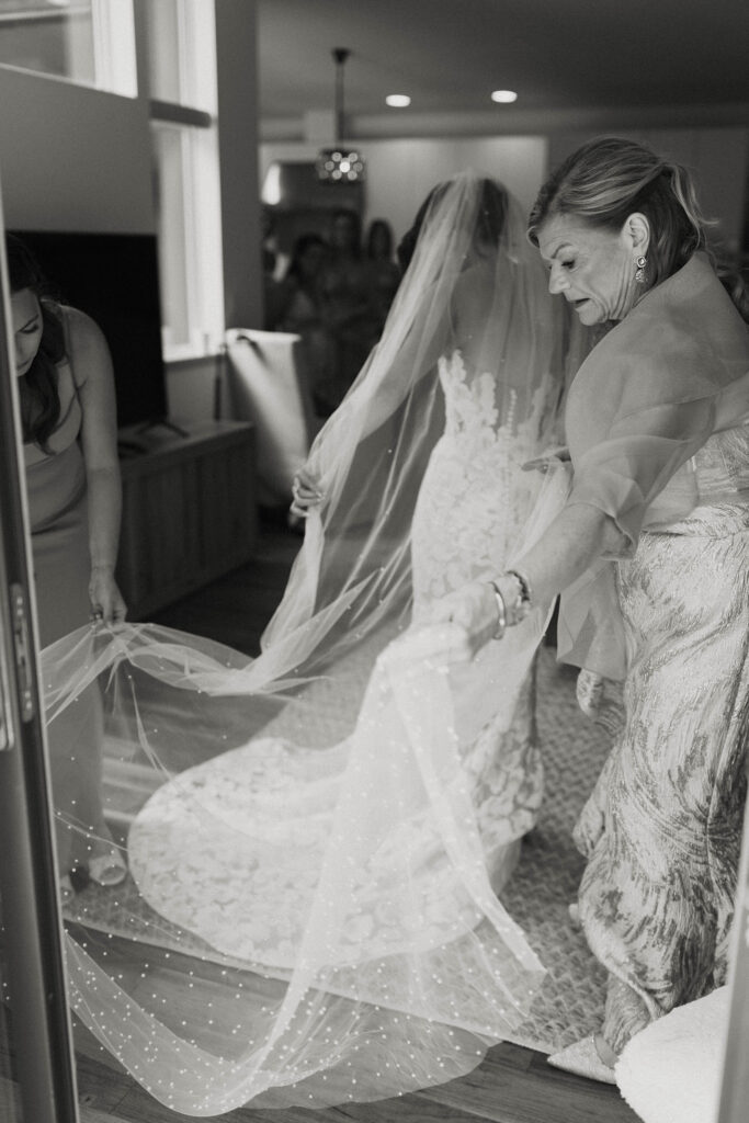 Bride's mom and bridesmaid helping bride with wedding veil inside at Nakoma Resort