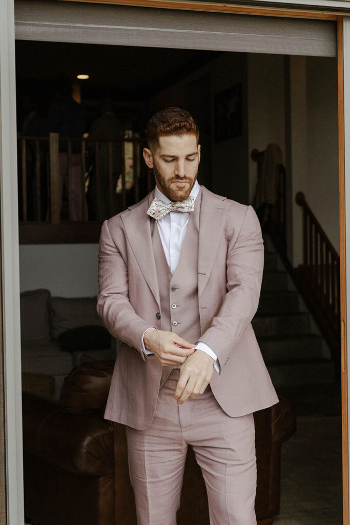 Groom adjusting shirt cuff on wedding attire while looking down at Nakoma Resort