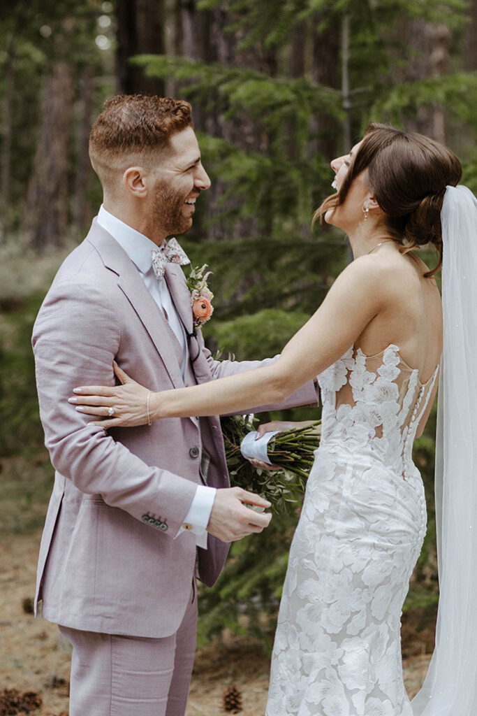 Wedding couple laughing together during first look with lots of trees in background at Nakoma Resort