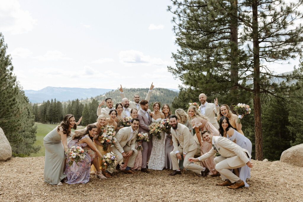 Wedding couple and bridal party posing together and celebrating with trees and mountains in background at Nakoma Resort
