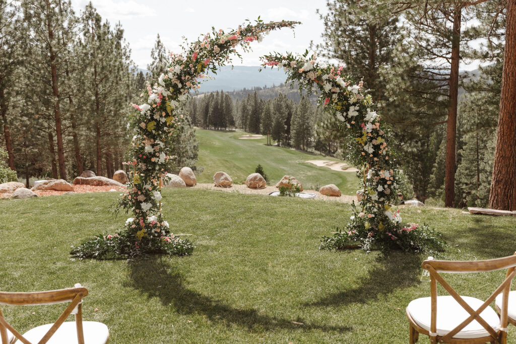 Colorful spires covered in florals forming wedding arch with grass and trees in background at Nakoma Resort