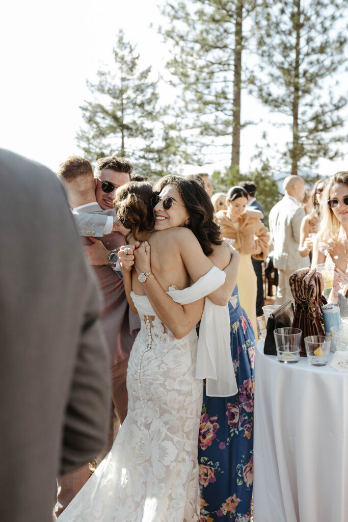 Bride hugging smiling wedding guest during cocktail hour at Nakoma Resort