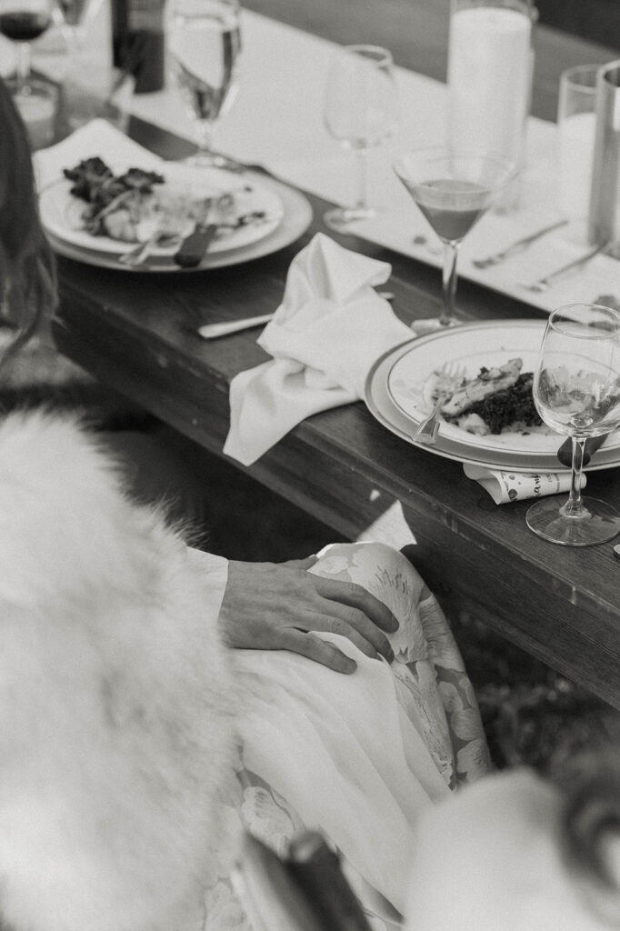 Close up of groom's hand on bride's leg during wedding dinner at Nakoma Resort