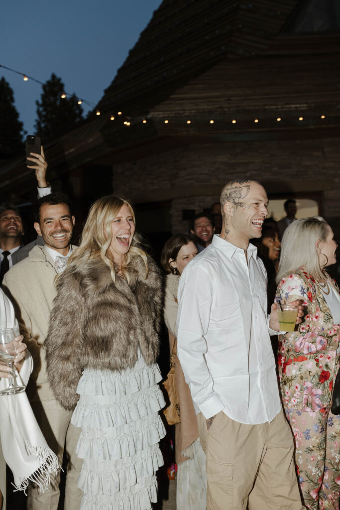 Wedding guests smiling with string lights above them during reception at Nakoma Resort