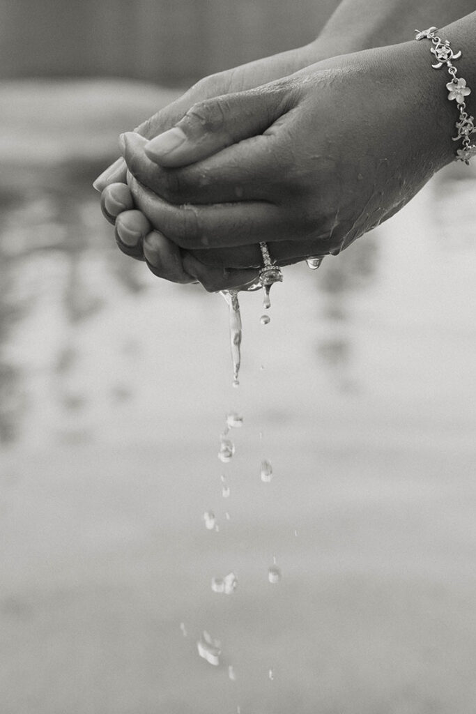 Woman's hands holding and dripping out water from bottom and off engagement ring in Lake Tahoe