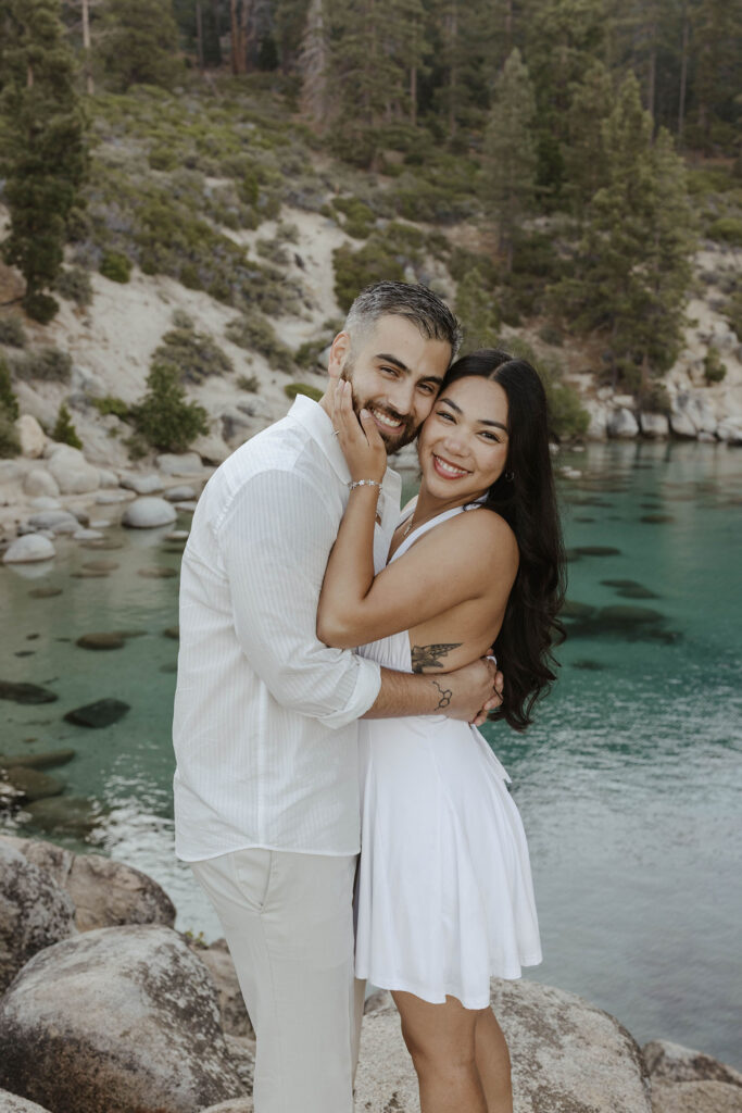 Engagement couple holding each other while smiling at camera with Lake Tahoe in background
