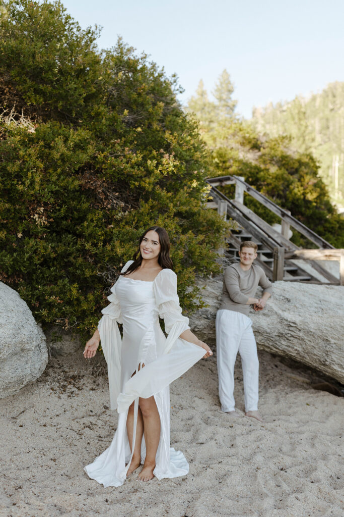 woman twirling in her dress smiling looking at the camera as man admires her from afar in lake tahoe