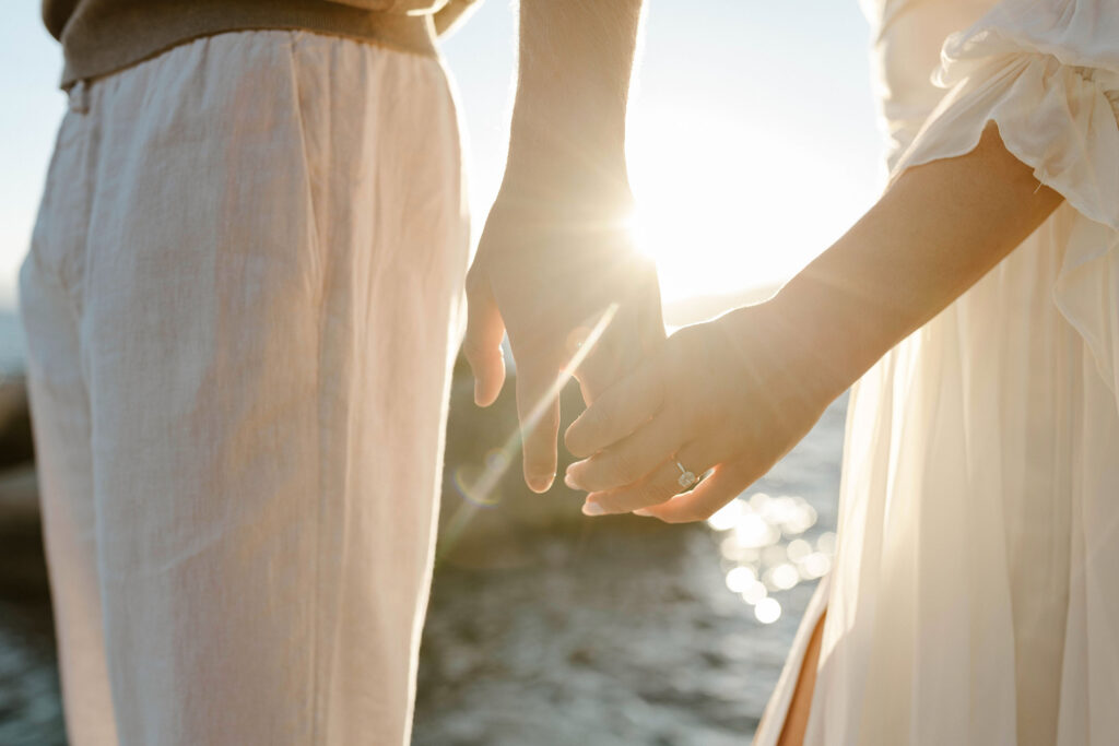 engagement couple holding hands showing engagement ring at sunset in lake tahoe