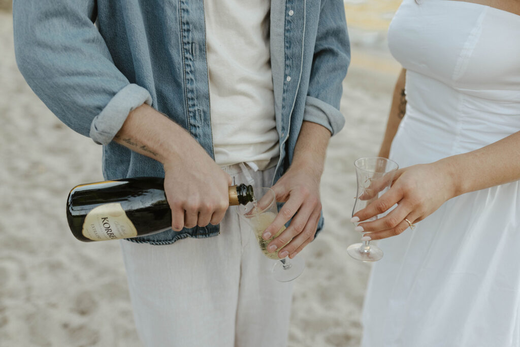 engagement couple pouring champagne on the beach in lake tahoe
