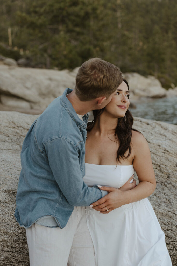 man kissing woman cheek as she looks in the distance in lake tahoe