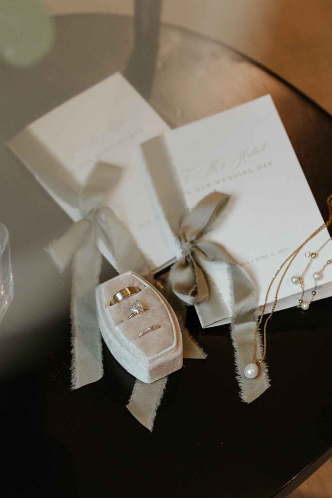 Wedding rings and announcements in flat lay on dark chair in South Lake Tahoe