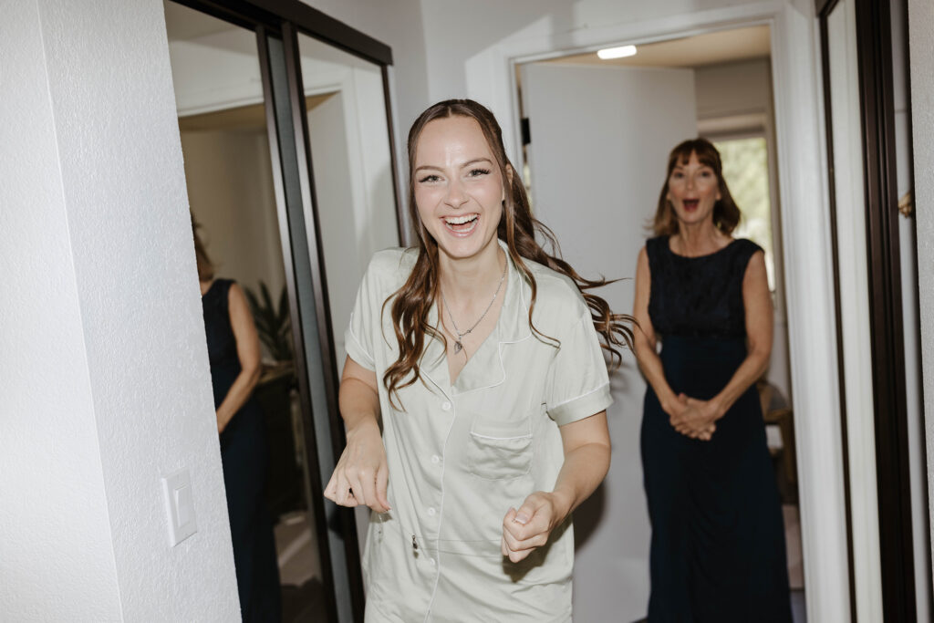 Bride holding necklace and smiling while mom smiles in background at South Lake Tahoe Elopement