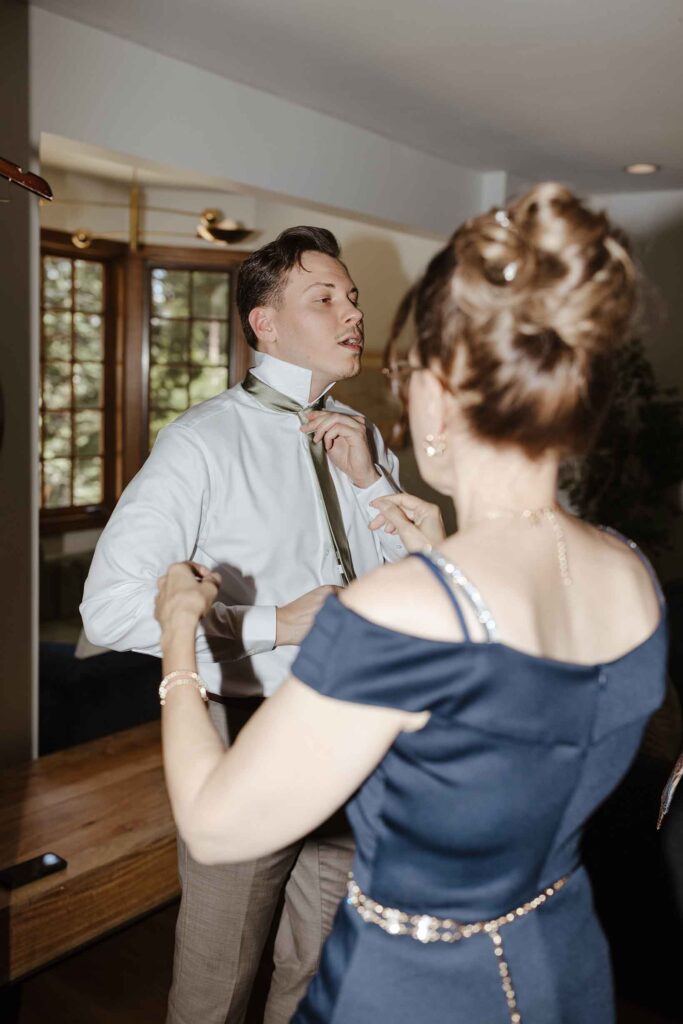 Elopement groom adjusting tie while mom comes over to help while inside at South Lake Tahoe