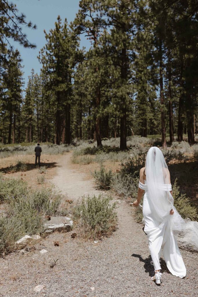 Elopement bride in wedding dress walking down trail towards groom before first look in South Lake Tahoe