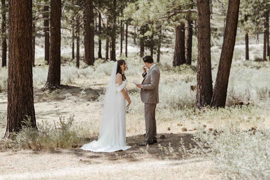 Elopement groom wiping tears while reading vows to bride in South Lake Tahoe with pine trees in background