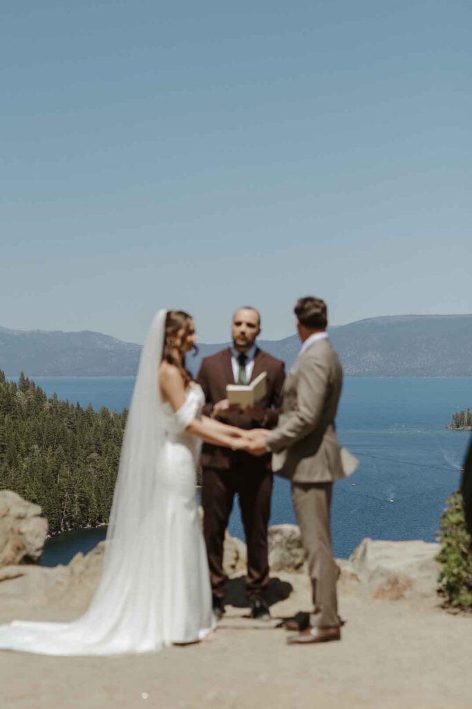 Groom looking out at Emerald Bay while holding bride's hands during elopement ceremony in South Lake Tahoe