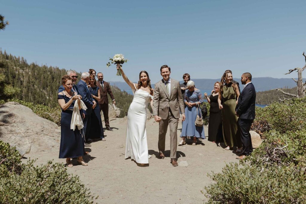 Wedding couple holding hands and celebrating while walking between guests after elopement ceremony in South Lake Tahoe