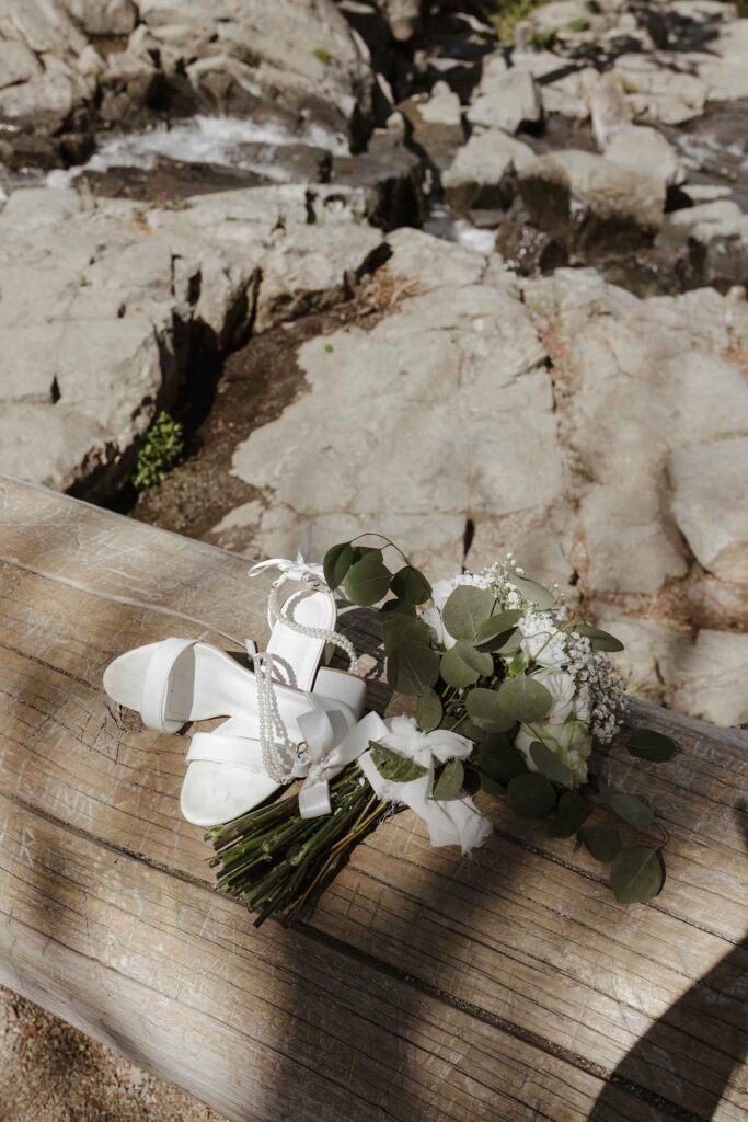 Floral bouquet and wedding shoes sitting on log together in South Lake Tahoe