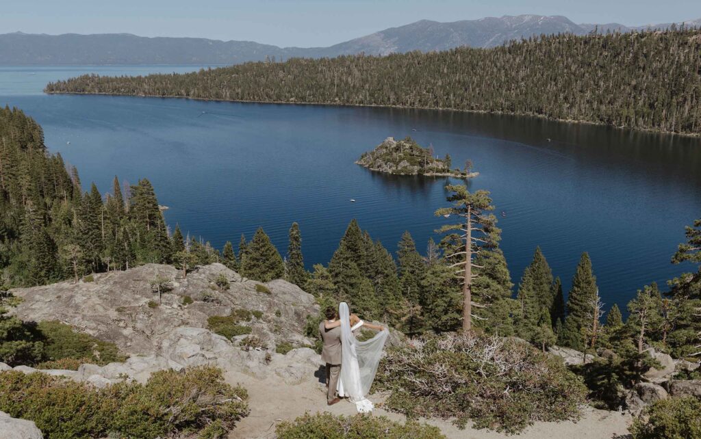 Elopement couple with arms around each other looking out over Emerald Bay in South Lake Tahoe