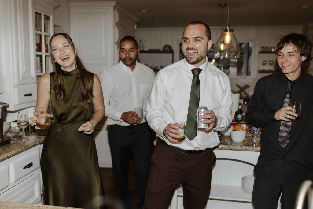 Wedding guests laughing and holding drinks while inside at South Lake Tahoe