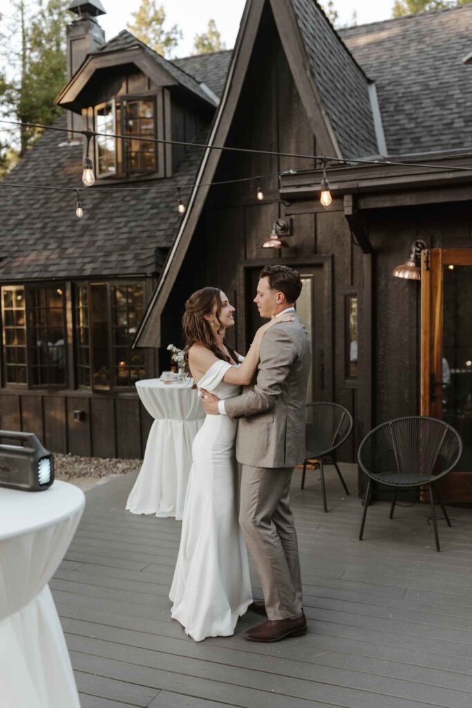 Elopement couple holding each other during first dance at reception in South Lake Tahoe in front of dark wooden building
