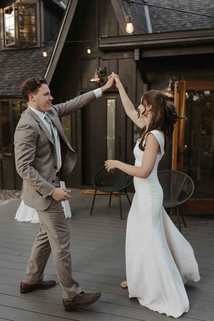 Elopement couple dancing and smiling during reception in front of dark wooden building in South Lake Tahoe