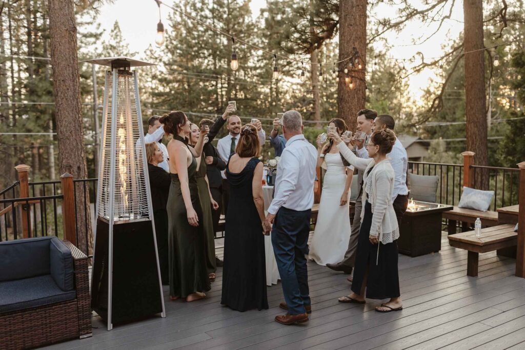 Elopement couple and guests all cheering drinks together during reception outside on wooden patio in South Lake Tahoe