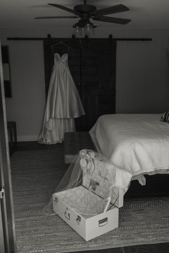Wedding dress hanging up in room in front of white trunk with shoes and veil hanging on edge at the Landing Tahoe Resort