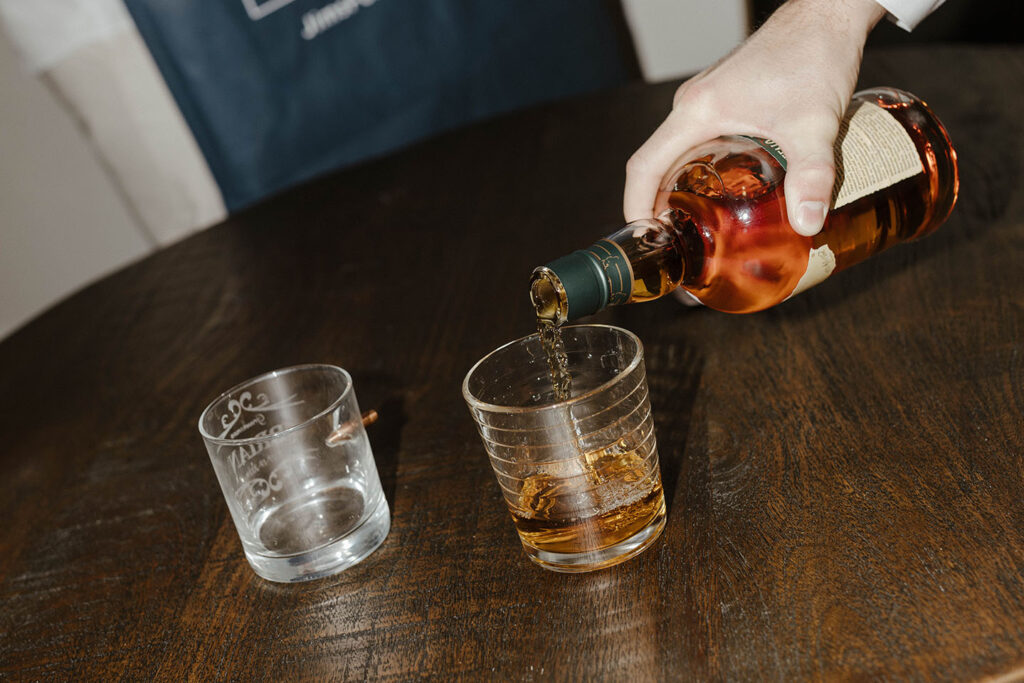 Close up of pouring alcohol in glass on dark wooden table