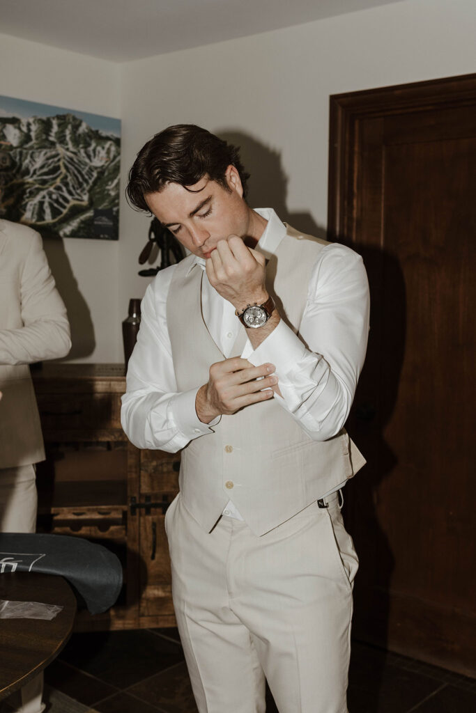 Groom buttoning sleeves on his wedding attire while inside at the Landing Tahoe Resort