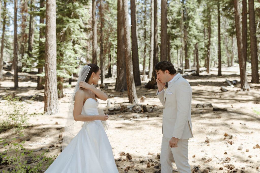 Groom emotional seeing bride during first look with pine trees in background at the Landing Tahoe Resort